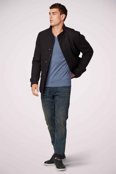 Pull col V bleu de Tom Tailor, porté avec un blouson noir et un jean foncé, sur un fond neutre.