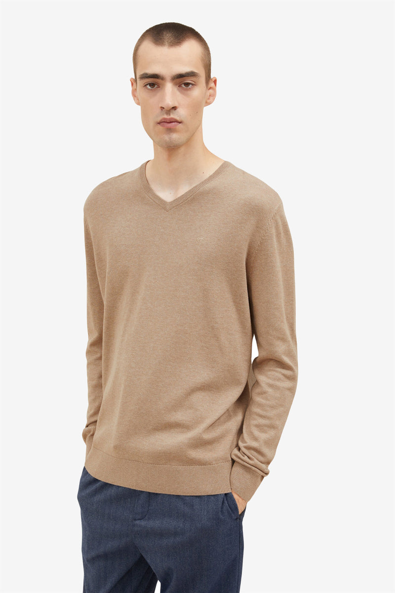 Pull col V beige de Tom Tailor, porté avec un pantalon bleu marine.