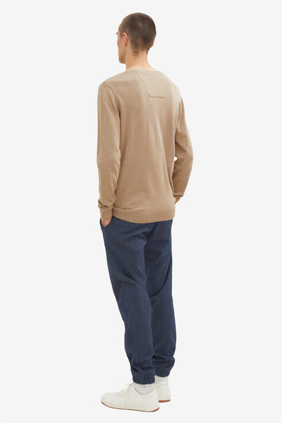 Pull col V beige par Tom Tailor, porté avec un pantalon bleu et des baskets blanches, vue de dos.