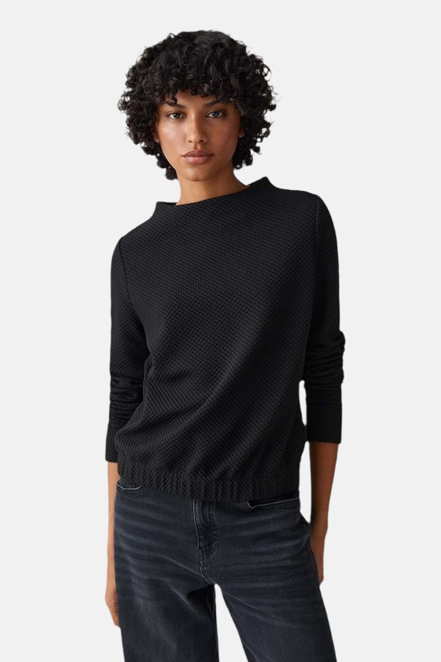 Pull à col rond noir d'OPUS avec une texture gaufrée, porté avec un jean noir.
