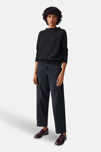 Pull à col rond noir d'OPUS, texturé, porté avec un jean large et des mocassins bordeaux.
