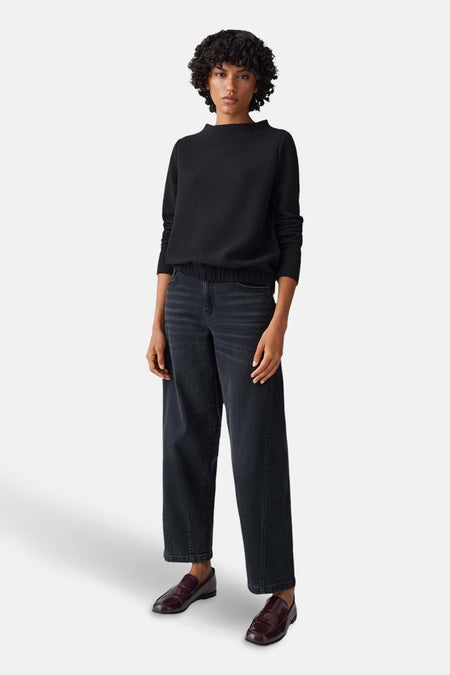 Pull à col rond noir d'OPUS, texturé, porté avec un jean large et des mocassins bordeaux.
