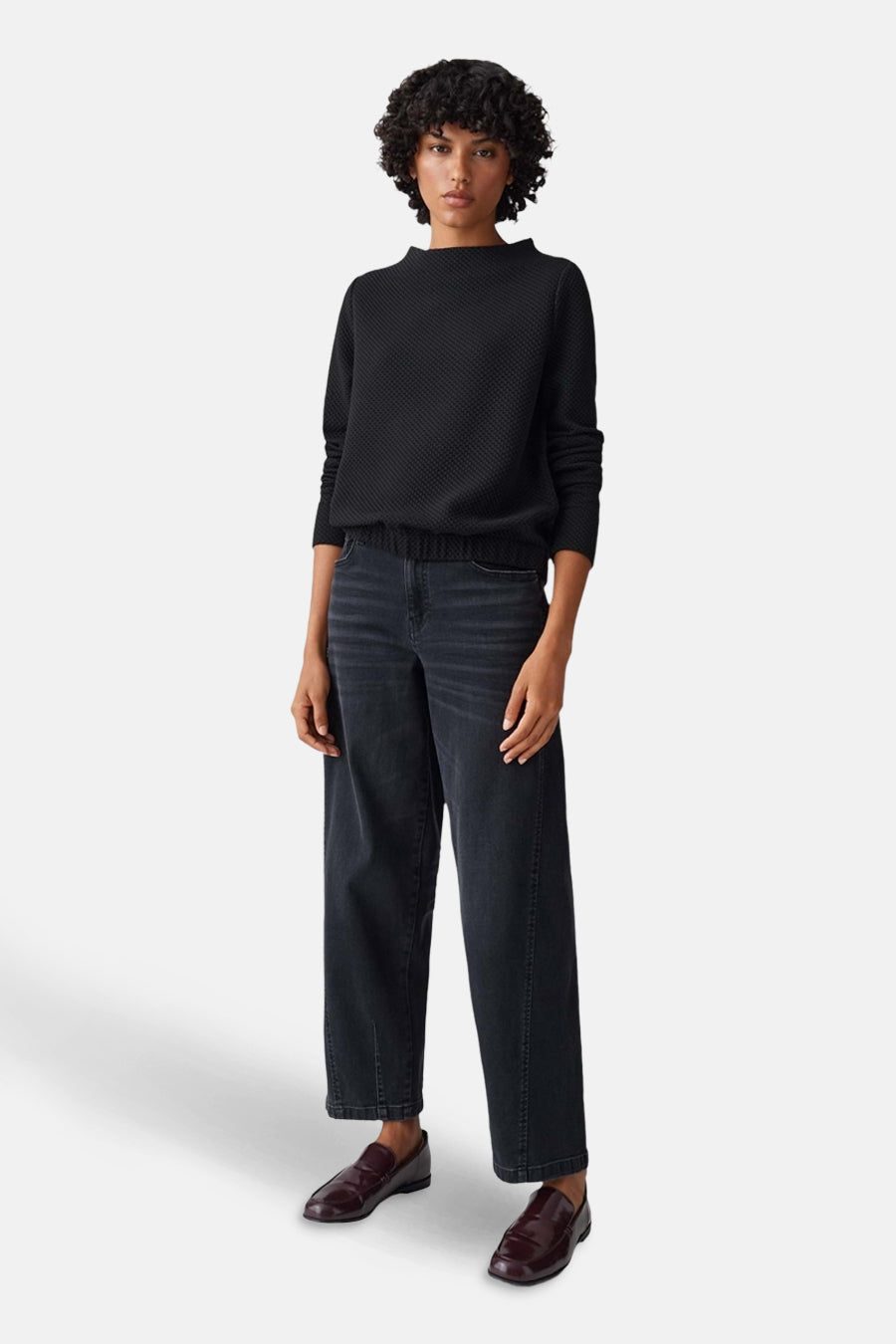 Pull à col rond noir d'OPUS, texturé, porté avec un jean large et des mocassins bordeaux.
