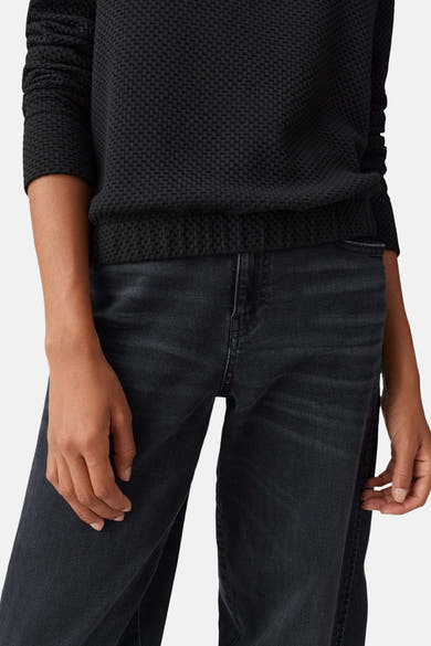 Pull à col rond noir d'OPUS avec motif texturé gaufré, porté avec un jean délavé.