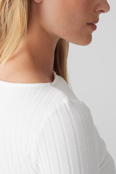 Pull à col rond blanc de OPUS, en maille côtelée, porté avec des cheveux blonds.
