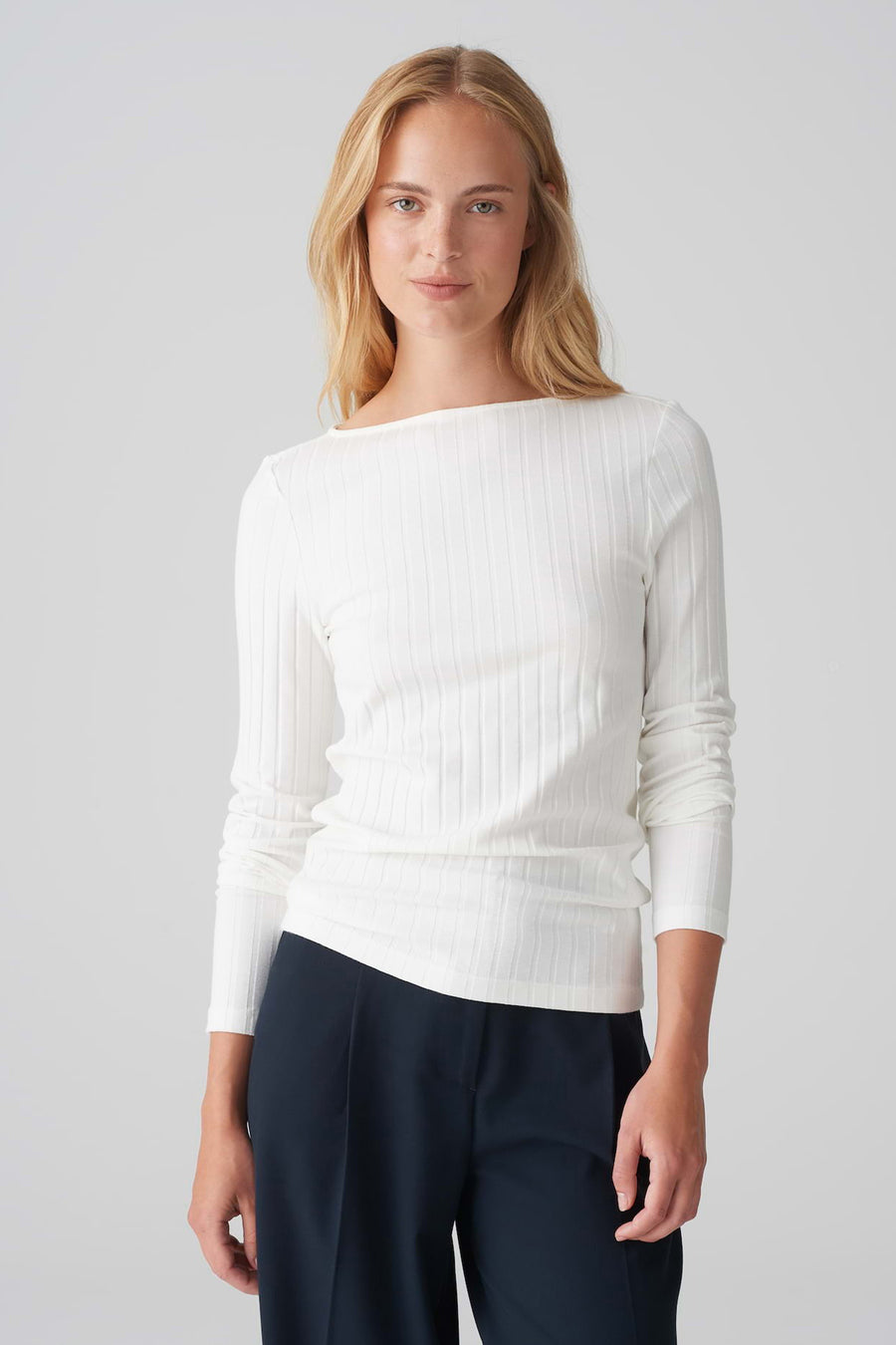 Pull à col rond blanc de OPUS en maille côtelée, porté avec un pantalon bleu marine.