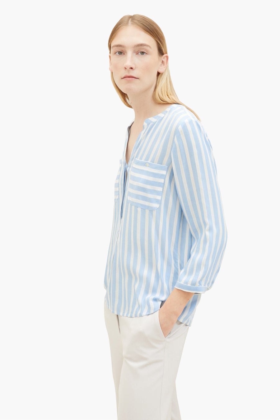 Blouse met lange mouwen van Tom Tailor, blauw gestreept, met borstzakken en beige broek gedragen.