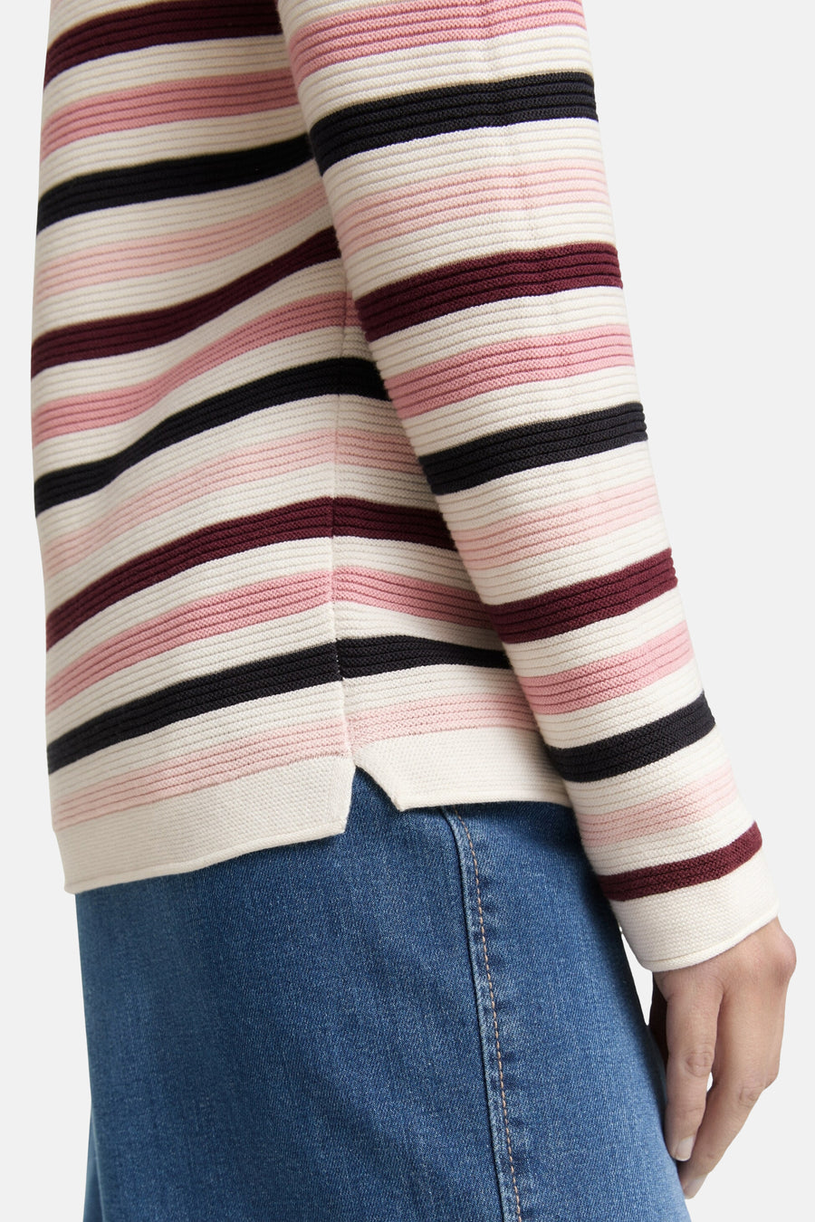 Multikleurige rondehals trui van Tom Tailor, met horizontale roze, zwarte en bordeauxrode strepen, gedragen met een blauwe jeans.