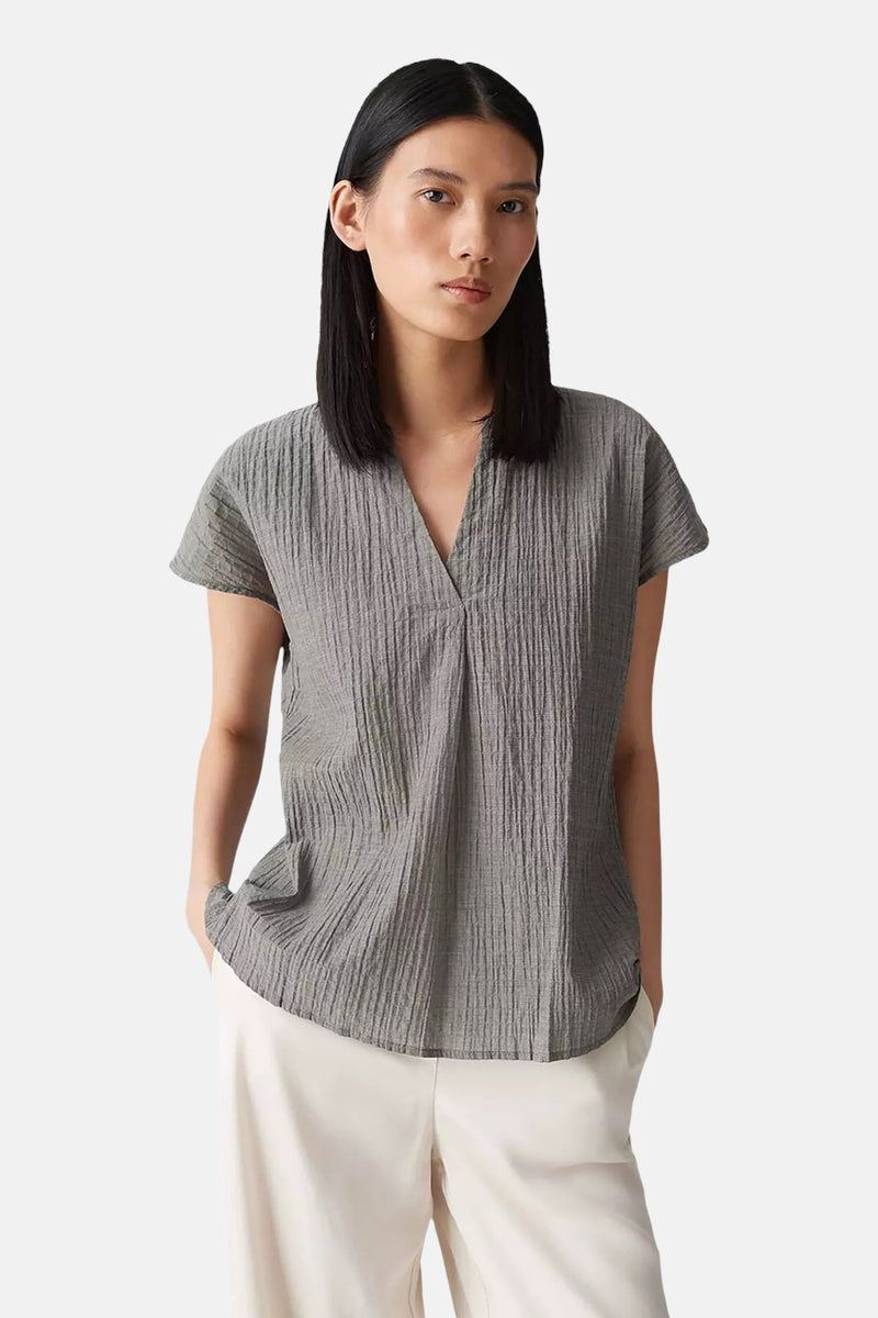 Kaki blouse met korte mouwen van OPUS, getextureerd met een V-hals, gedragen met een witte broek.