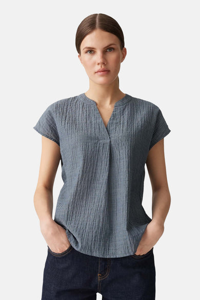 Blouse bleue à manches courtes d'OPUS, en tissu texturé, portée avec un jean foncé.