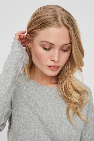 Pull gris à col rond de VERO MODA, en tricot uni, porté avec les cheveux blonds lâchés.