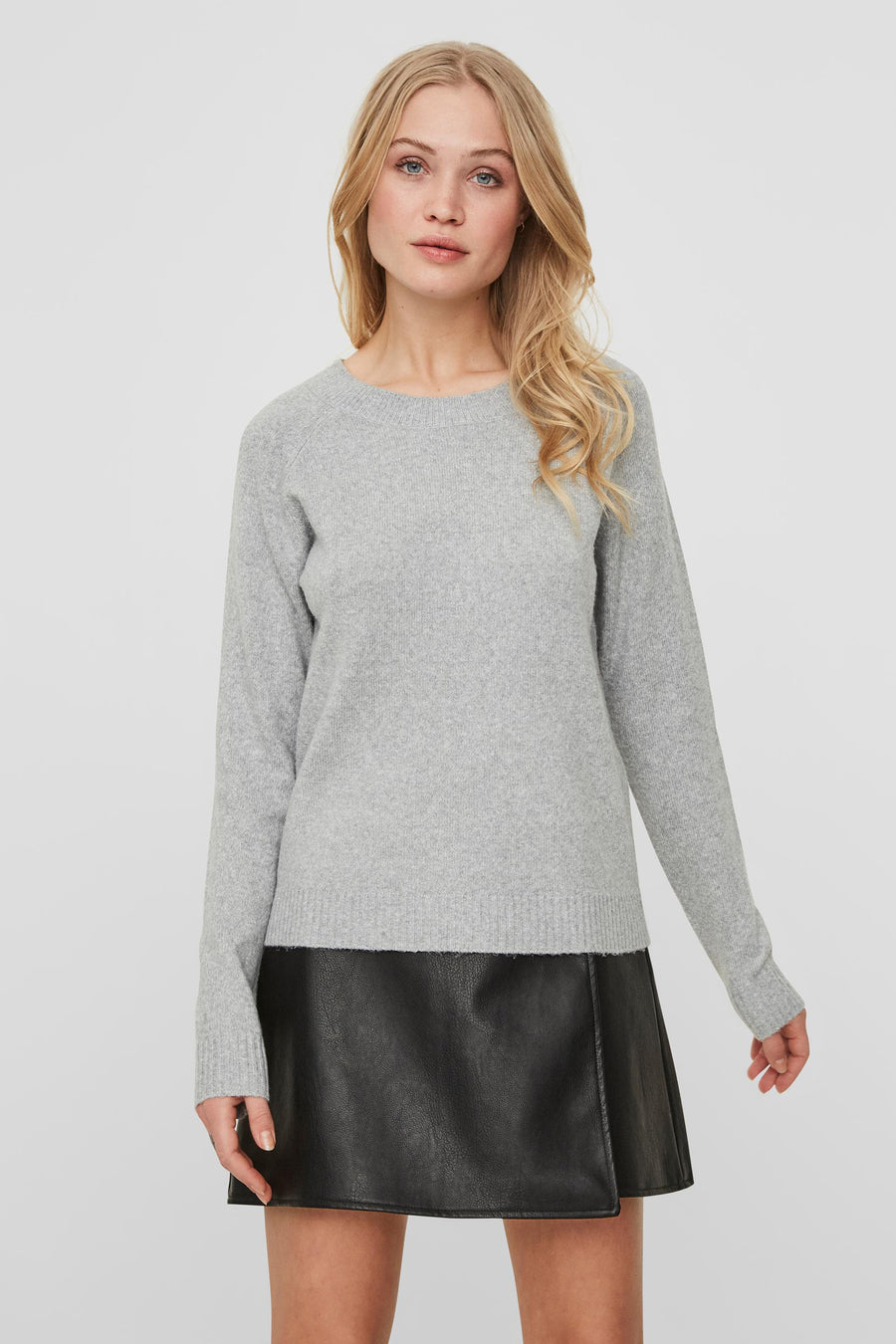 Pull gris de VERO MODA, porté avec une jupe courte en similicuir noir.
