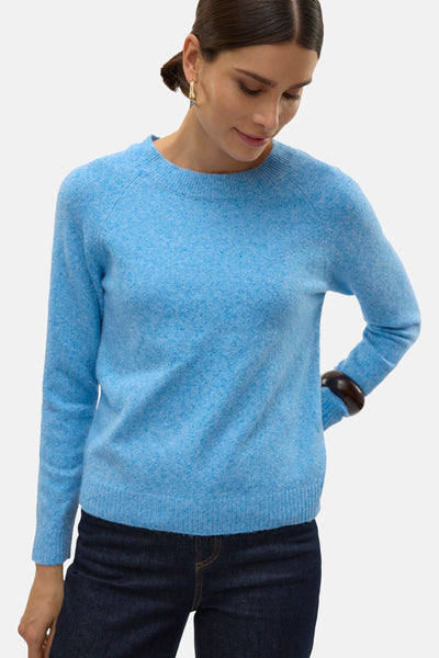 Pull à col rond bleu de VERO MODA, en maille duveteuse, porté avec un jean foncé et un bracelet en bois.