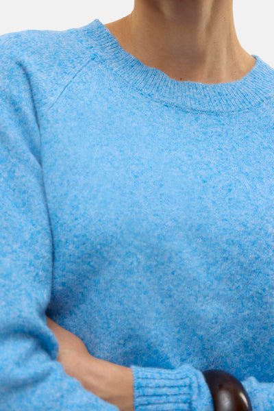 Pull à col rond bleu de VERO MODA, en maille texturée, porté avec un bracelet marron.