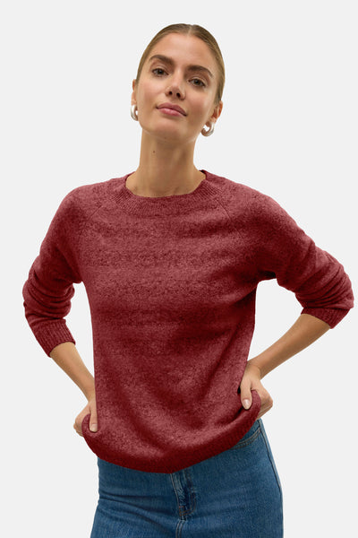Pull à col rond rouge de VERO MODA porté avec un jean bleu et des boucles d'oreilles argentées.