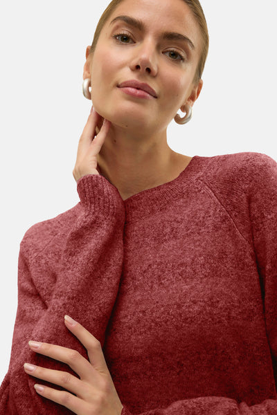 Pull à col rond rouge de VERO MODA, en maille douce, porté avec des boucles d'oreilles argentées.
