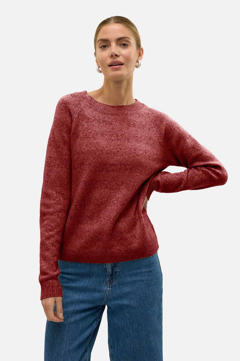 Pull à col rond rouge de VERO MODA, porté avec un jean taille haute et des boucles d'oreilles argentées.

