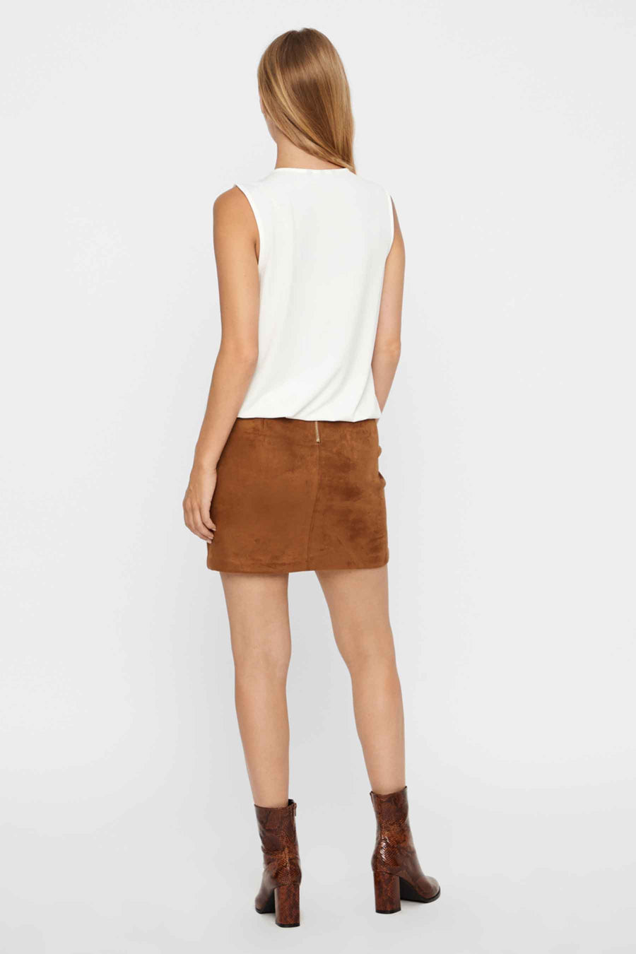 Mini-jupe marron en daim de Vero Moda, vue de dos, portée avec un haut blanc et des bottines à motifs serpent.
