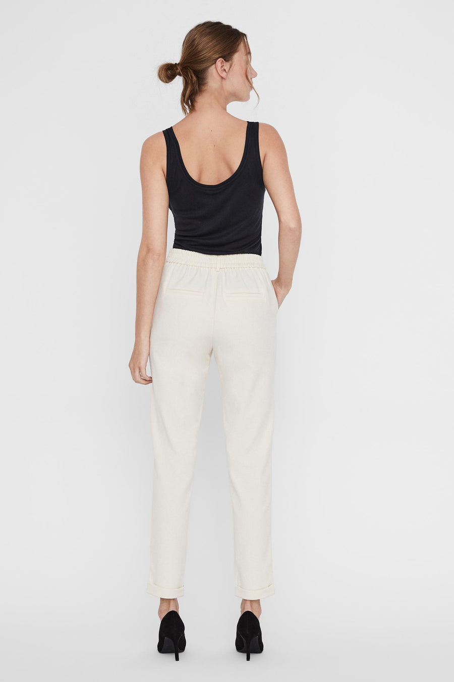 Pantalon de tailleur beige de Vero Moda, porté avec un débardeur noir et des escarpins noirs, vue arrière.