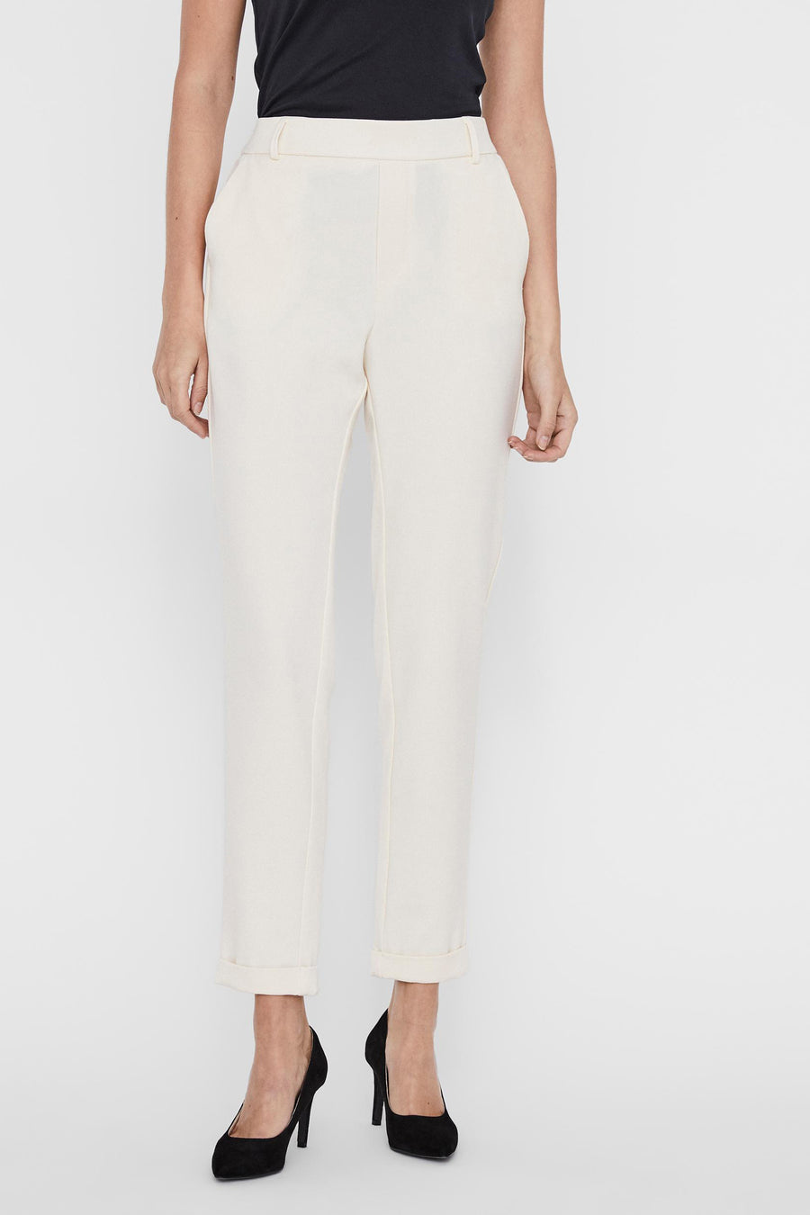 Pantalon de costume beige de Vero Moda, avec ourlets roulés et porté avec un t-shirt noir et des escarpins noirs.