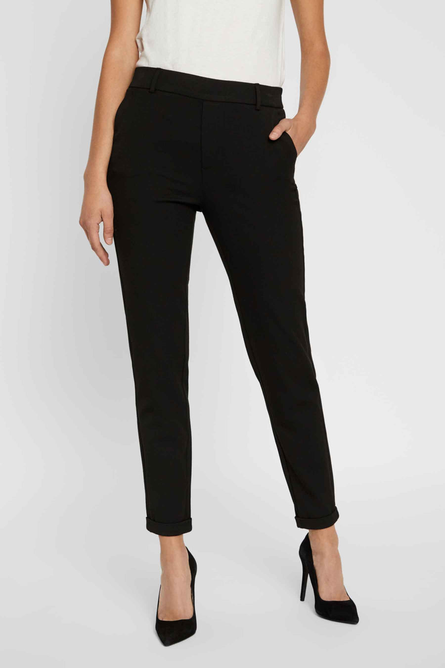 Pantalon de costume noir de Vero Moda, porté avec des escarpins noirs et un haut blanc.