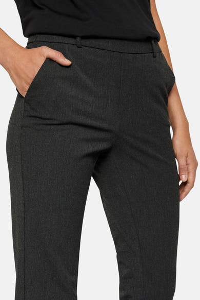 Pantalon de costume gris par Vero Moda, avec une main dans la poche, porté avec un t-shirt noir.