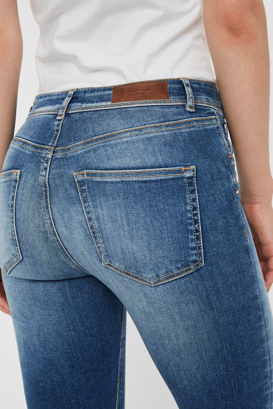 Jean skinny bleu moyen de VERO MODA, avec poches arrière, détail de surpiqûres et empiècement en cuir à la taille.