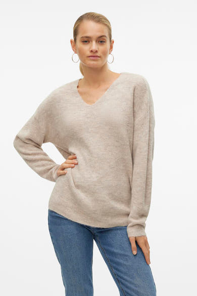 Pull col V écru de VERO MODA, avec des manches longues et porté avec un jean bleu.