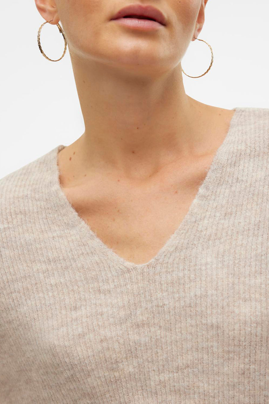 V-hals trui in ecrukleurige gebreide stof van VERO MODA, met gouden oorbellen.