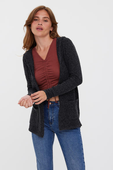 Gilet noir de VERO MODA, porté par-dessus un haut en maille côtelée couleur rouille et un jean bleu.
