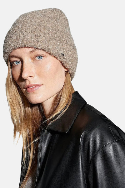 Bonnet taupe brillant de OPUS, porté avec une veste en cuir noire.
