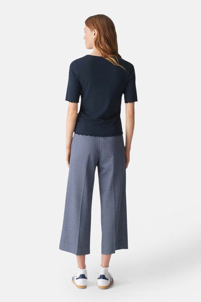 Pull à col rond bleu de OPUS avec des manches courtes à bord festonné, porté avec un pantalon bleu ample.