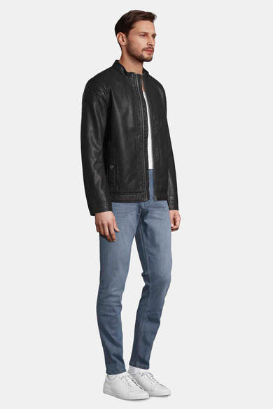 Veste en simili cuir noire de Tom Tailor, portée avec un jean bleu et des baskets blanches, vue de côté.