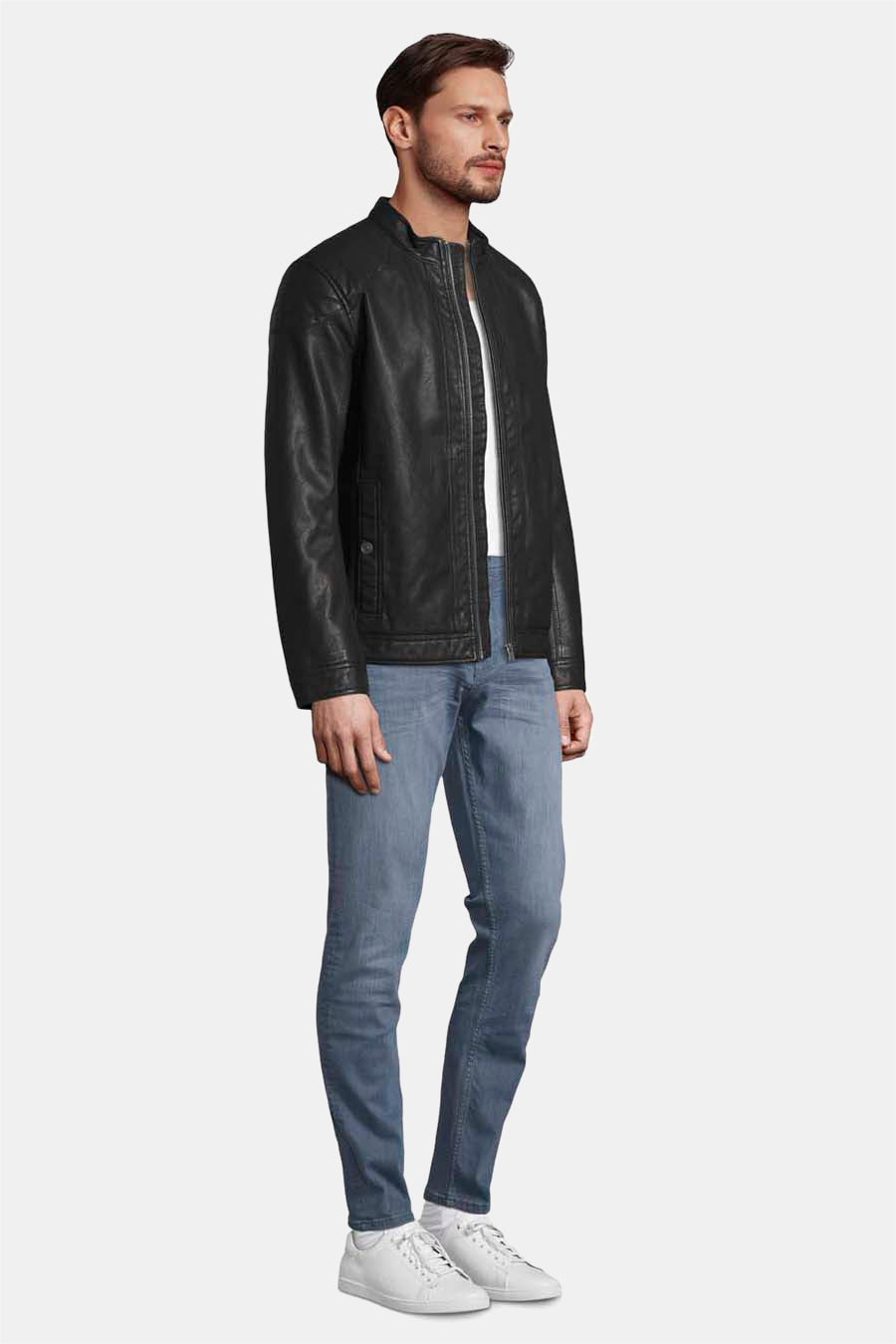 Veste en simili cuir noire de Tom Tailor, portée avec un jean bleu et des baskets blanches, vue de côté.