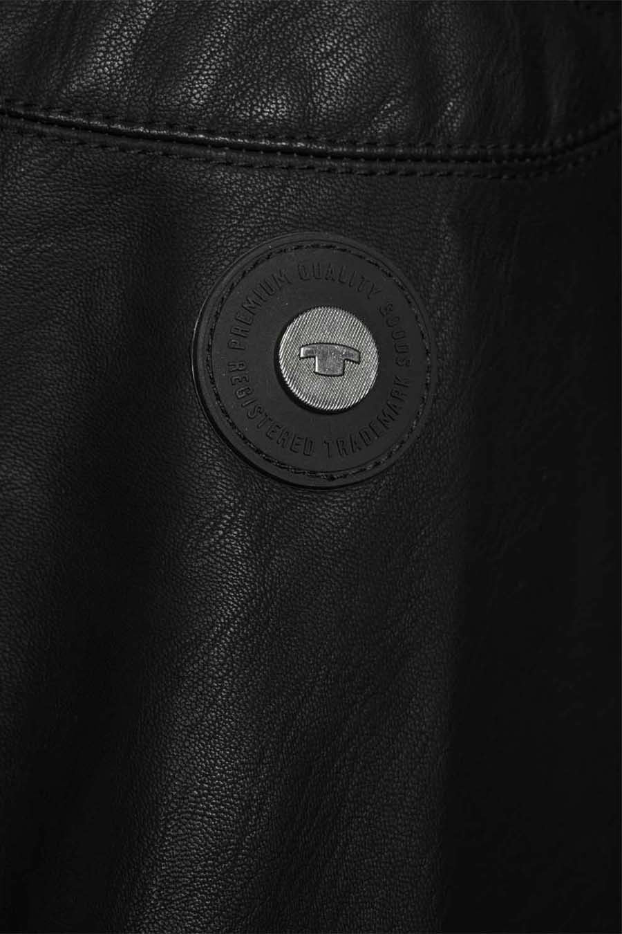 Veste en simili cuir noire de Tom Tailor, avec écusson de la marque visible.