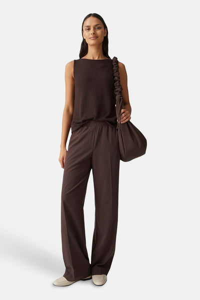 Top sans manches brun par OPUS, porté avec un pantalon taille haute et un sac assorti.