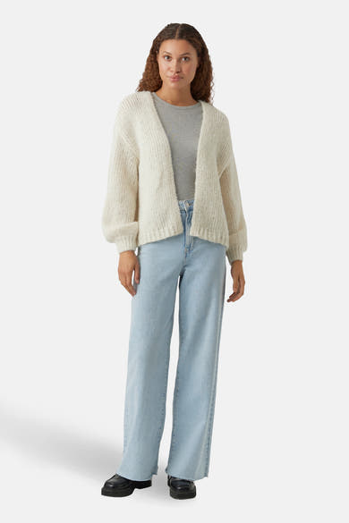 Beige vest van VERO MODA®, gedragen over een effen grijs T-shirt en een lichtblauwe wijde jeans.