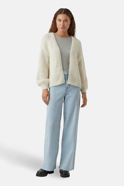 Beige vest van VERO MODA®, gedragen over een effen grijs T-shirt en een lichtblauwe wijde jeans.