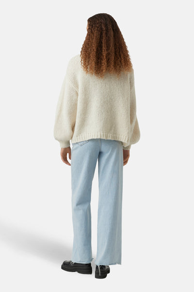 Beige gebreid vest van VERO MODA, met ballonmouwen en een rechte zoom, gedragen met een wijde jeans.