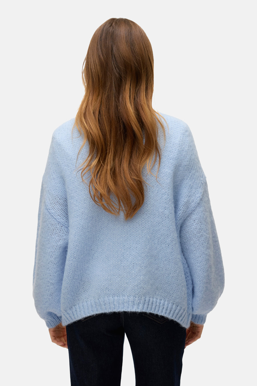 Cardigan bleu clair de VERO MODA, manches longues amples, texture douce et cheveux roux ondulés, vue de dos.

