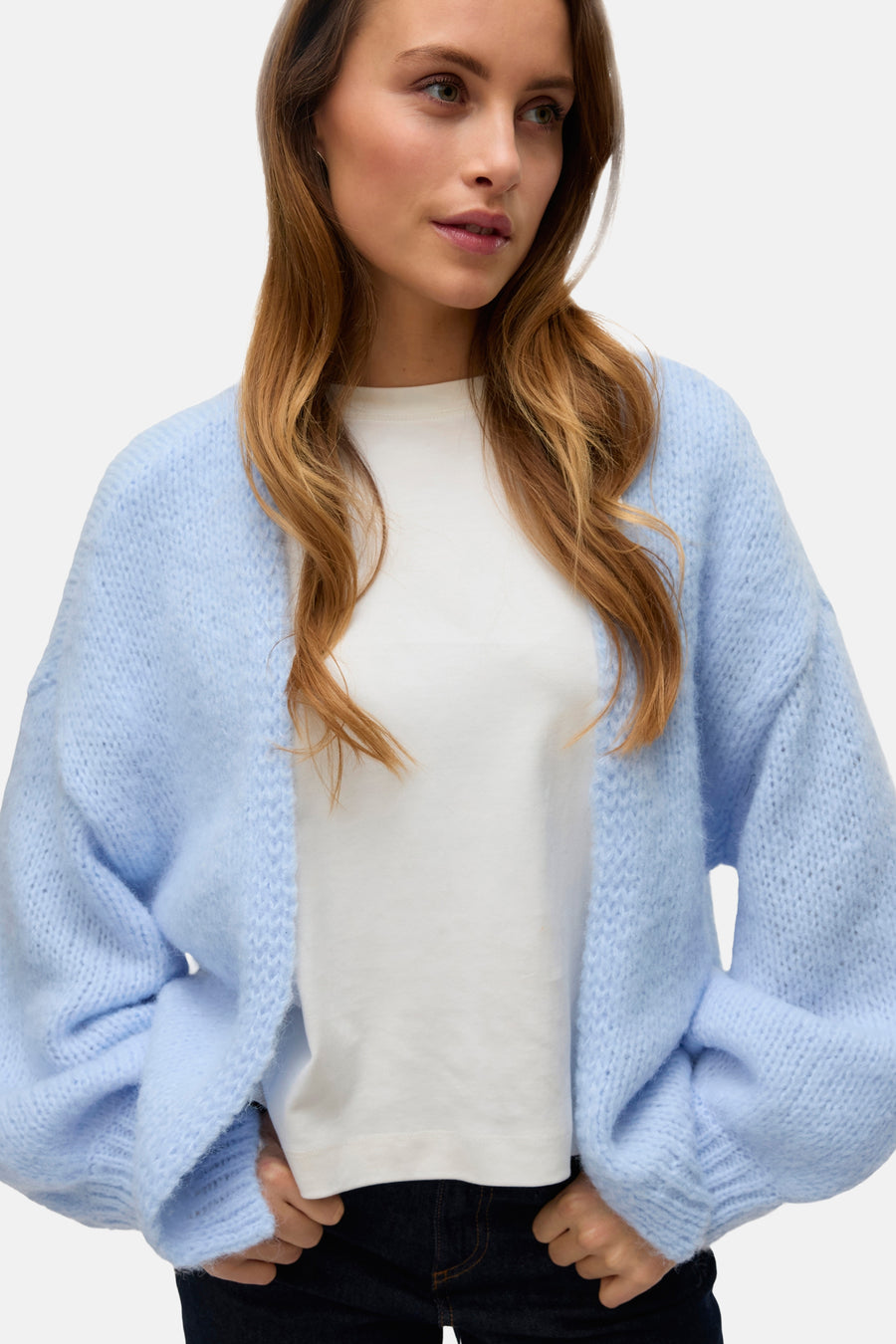 Cardigan bleu de VERO MODA, porté sur un t-shirt blanc et un pantalon foncé.