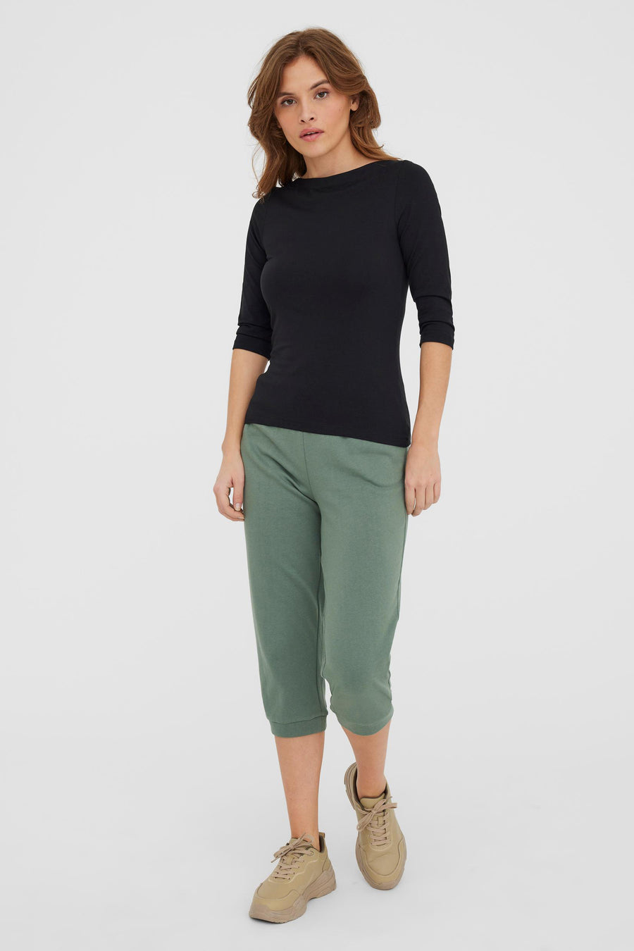 Effenchez zwart T-shirt met lange mouwen van VERO MODA, gedragen met een olijfgroene capri en beige sneakers.