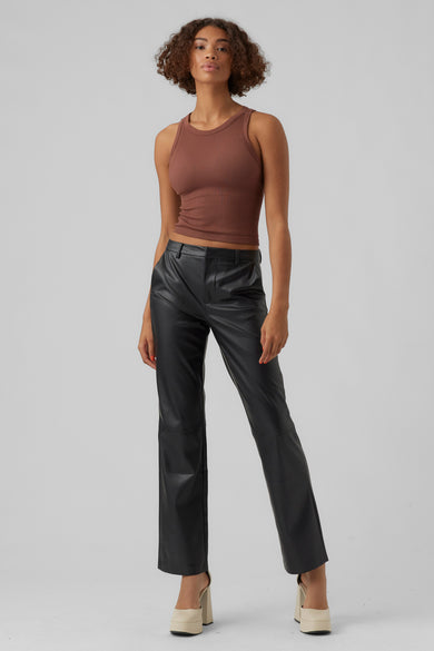 Pantalon noir de VERO MODA® en similicuir, porté avec un débardeur marron côtelé et des chaussures à plateforme couleur crème.
