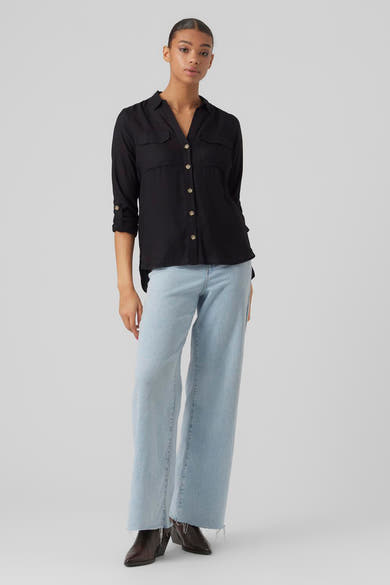 Chemisier noir à manches longues de VERO MODA, avec poches à rabat et boutons dorés, porté avec un jean bleu.