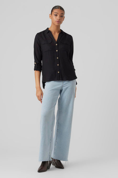 Chemisier noir à manches longues de VERO MODA, avec poches à rabat et boutons dorés, porté avec un jean bleu.