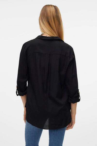 Chemisier noir à manches longues de VERO MODA, avec patte de boutonnage au dos et porté avec un jean.
