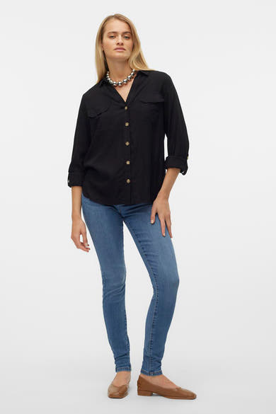 Chemise noire à manches longues de Vero Moda, portée avec un collier argenté et un jean bleu.