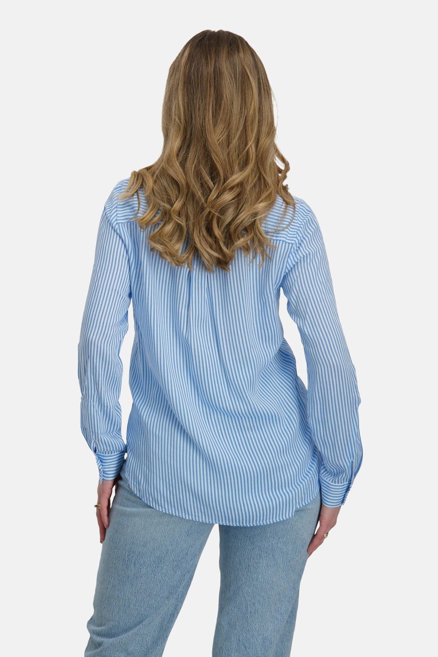 Chemise à manches longues bleue à rayures, de VERO MODA®, avec des plis au dos et un jean clair.