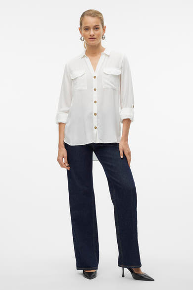 Chemisier blanc à manches longues de VERO MODA, porté avec un jean bleu et des escarpins noirs.