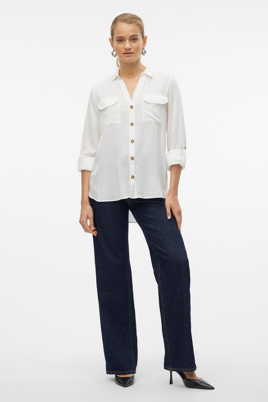 Chemisier blanc à manches longues de VERO MODA, porté avec un jean bleu et des escarpins noirs.